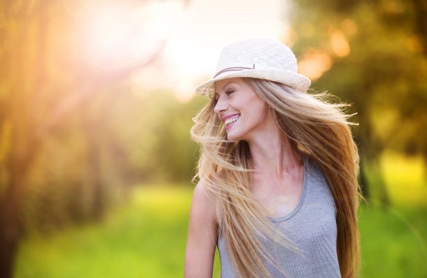 happy blonde woman outdoor white hat on the head green sunny background hair dryers best bio ionic